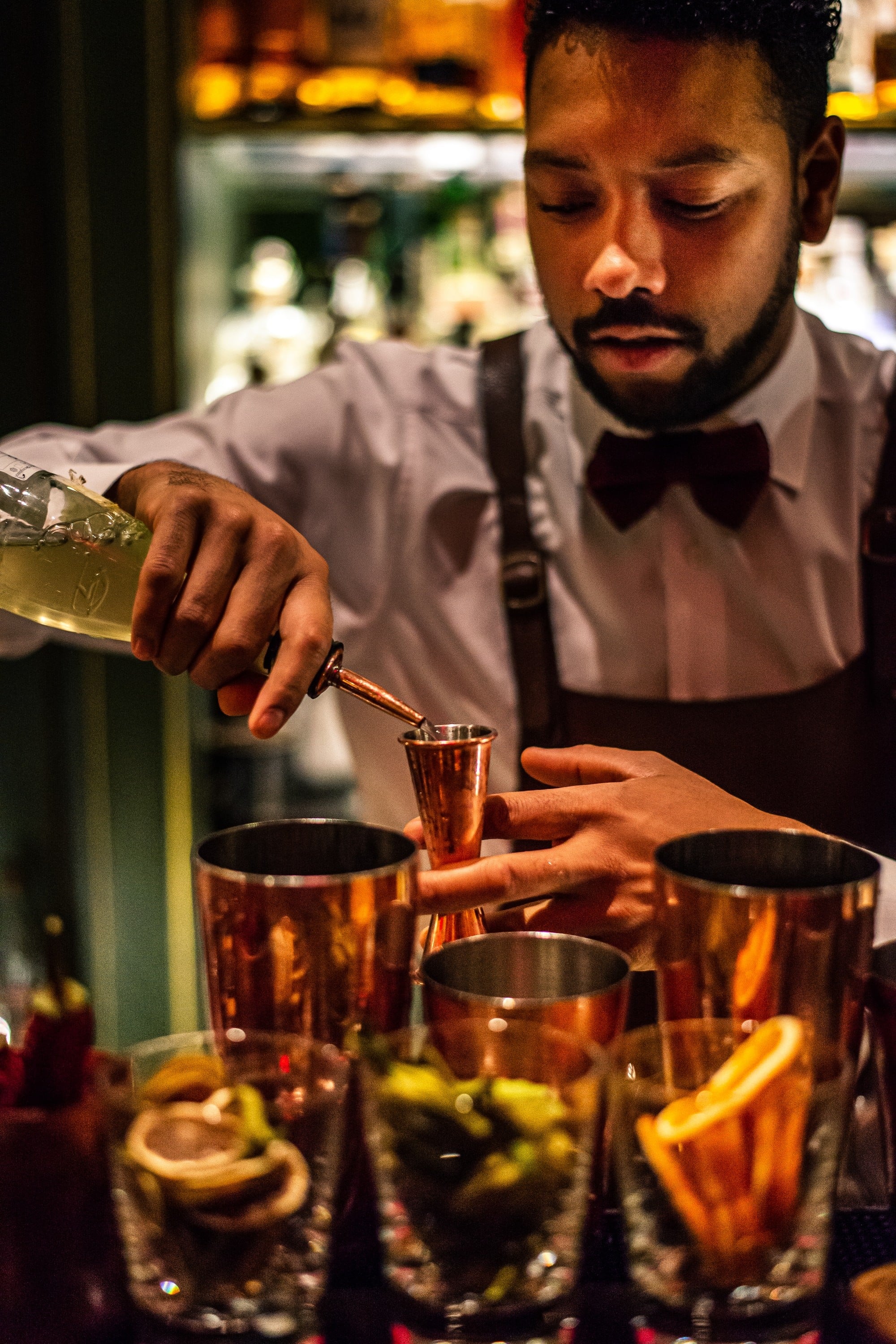 a bartender is preparing a cocktail by pouring with the jigger